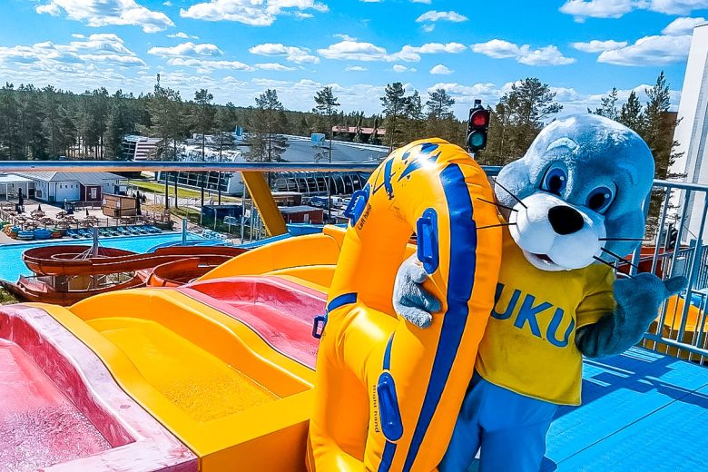 Jukupark Kalajoen maskotti vilkuttaa vesiliukumäen huipulla.
