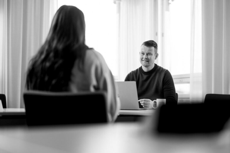 HR-asiantuntija haastattelee pöydän ääressä ehdokasta joka on kuvassa selin kameraan